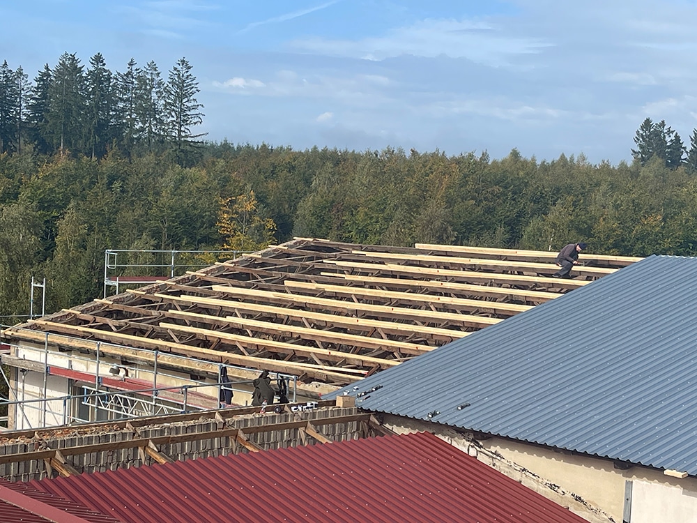 Dachneueindeckung mit Trapezblech: Holzkonstruktion und Dachsparren auf Gewerbebau während der Sanierung