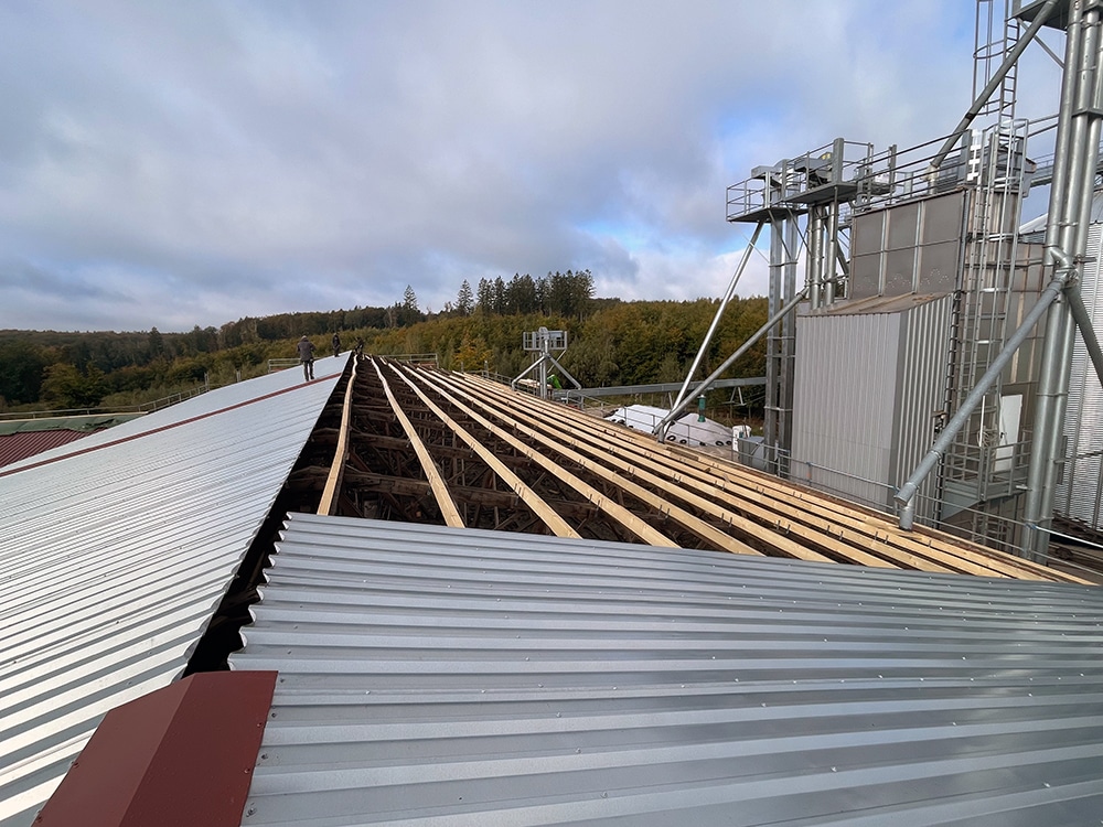Dachneueindeckung mit Trapezblech: Baustelle mit verlegten Metallprofilen und Holzunterkonstruktion auf Gewerbegebäude