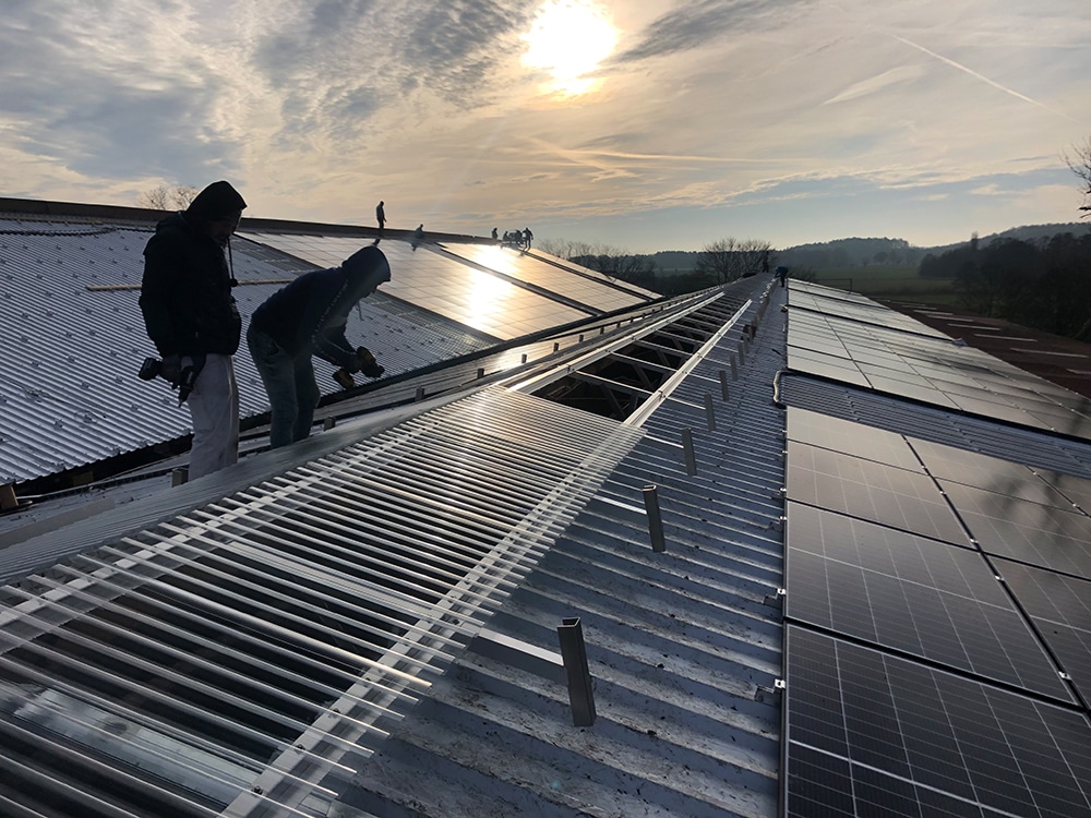 Dachdecker bei der Dachneueindeckung mit Trapezblech und Solaranlagen-Montage auf Gewerbegebäude