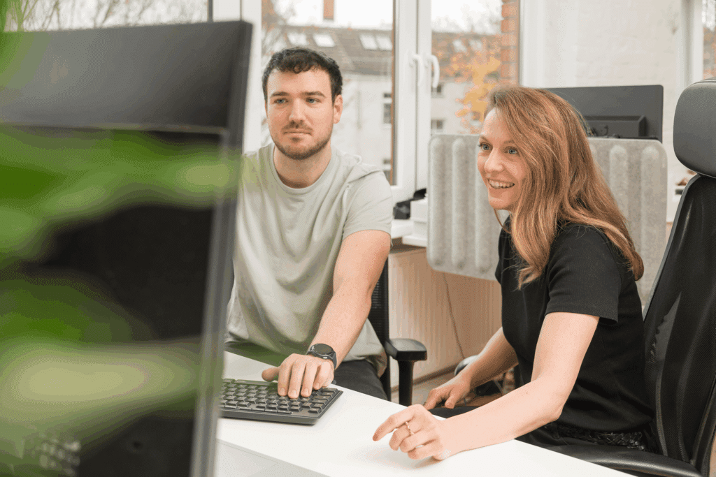 Zwei Mitarbeiter von K&O Dach- & Bauservice arbeiten gemeinsam am Computer im Büro