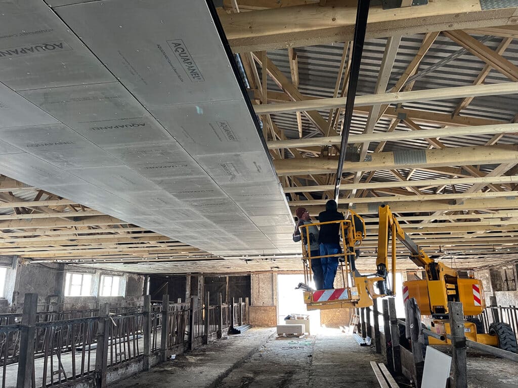 Arbeiter auf Hubarbeitsbühne bei der Dachneueindeckung mit Trapezblech in einer Gewerbehalle