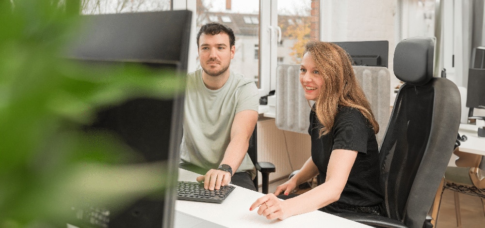 Zwei Mitarbeiter von K&O Dach- & Bauservice im Büro am Computer bei der Planung von Bauprojekten